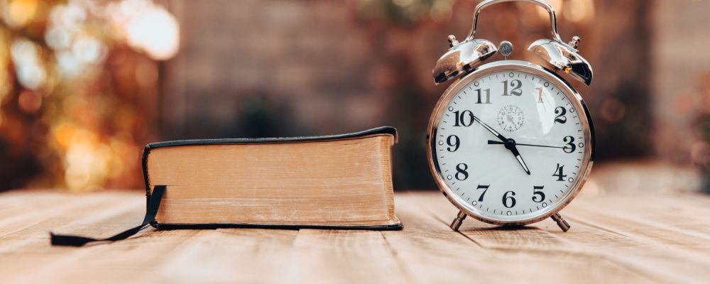 Book and clock on a wooden table